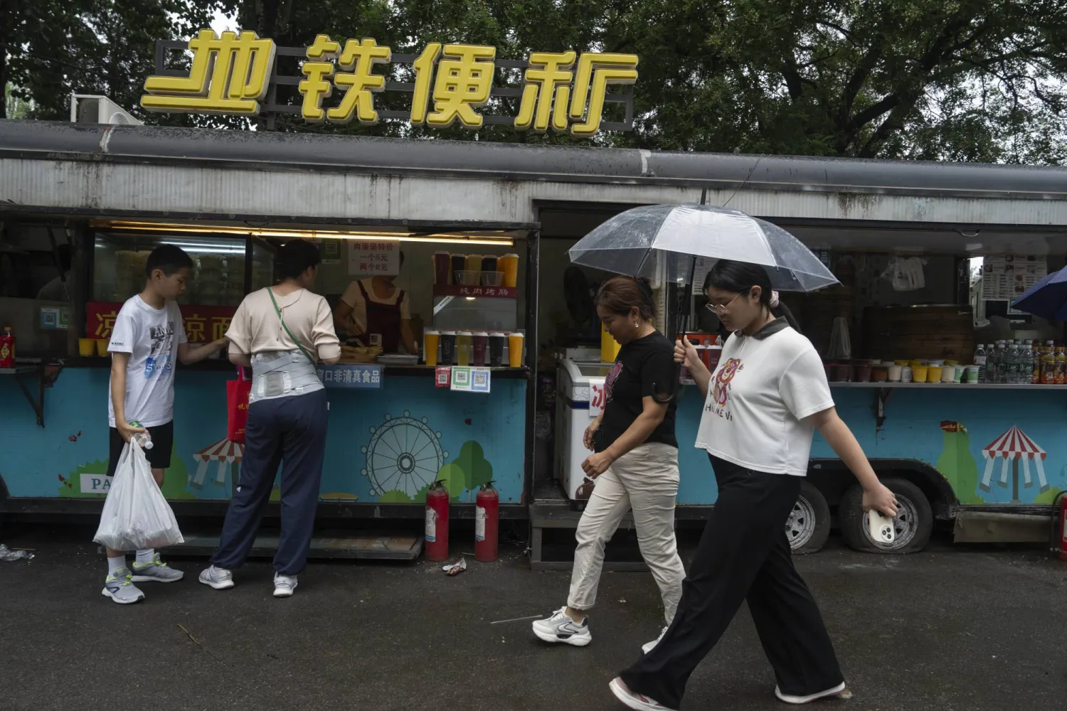 مشاة يسيرون تحت المظلات في أحد شوارع العاصمة الصينية بكين وسط أمطار غزيرة (أ.ب)