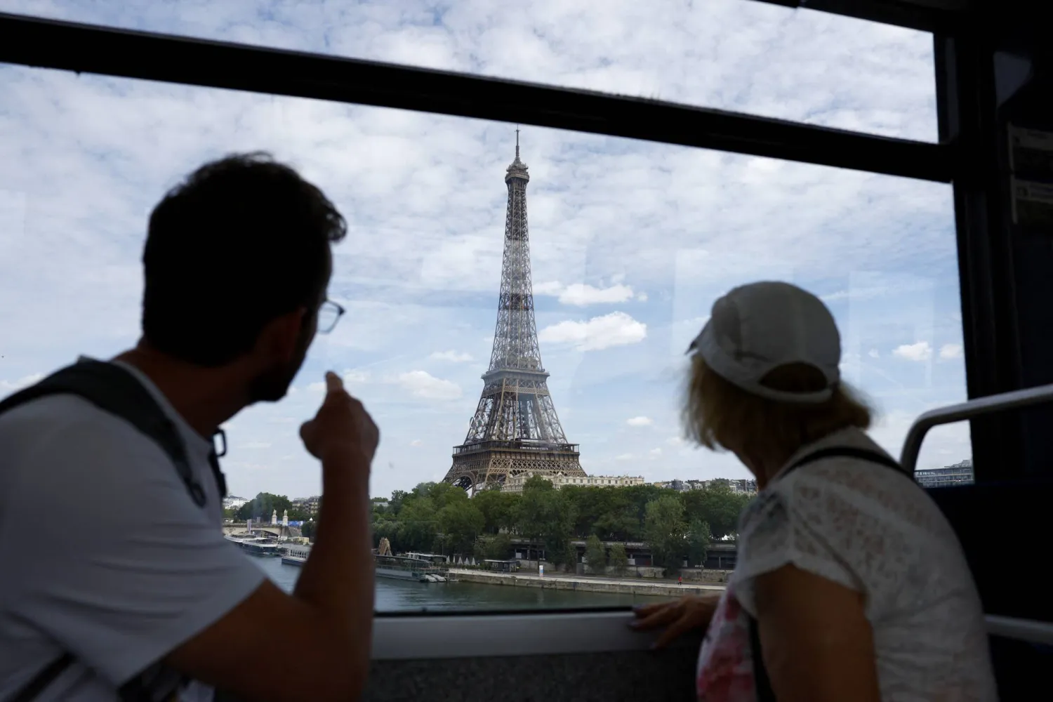 راكبان في قطار مترو بباريس يشيران إلى برج إيفل (رويترز)