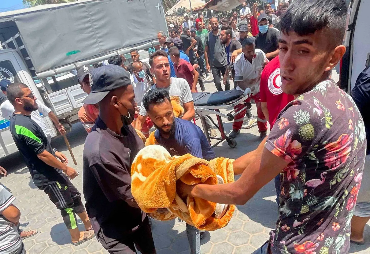 فلسطينيون يحملون جريحاً في مستشفى «شهداء الأقصى» في أعقاب غارة إسرائيلية بدير البلح (رويترز)