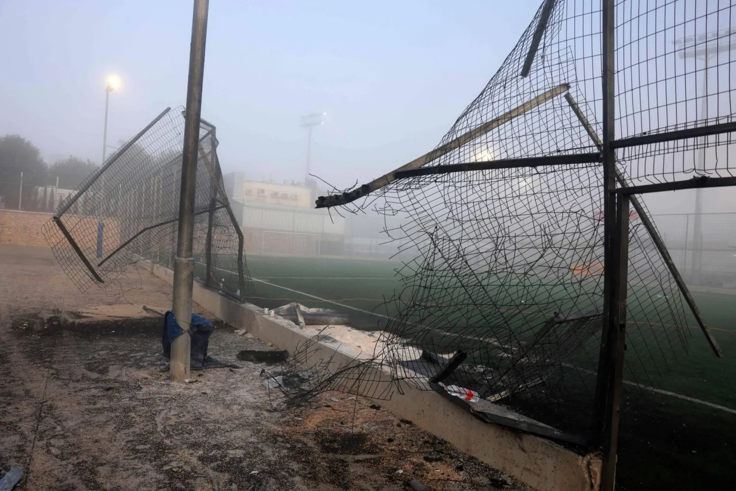 A damaged gate and debris are seen at a football pitch after a reported strike from Lebanon fell in Majdal Shams village in the Israeli-annexed Golan area on July 28, 2024. (Photo by Menahem Kahana / AFP)