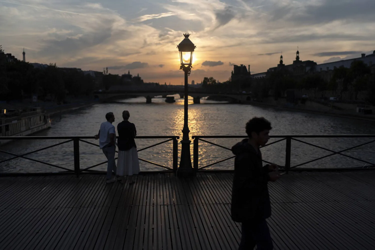 The sun sets over the Seine river next to the Louvre museum, at right, during the 2024 Summer Olympics, Saturday, July 27, 2024, in Paris. (AP Photo/David Goldman)