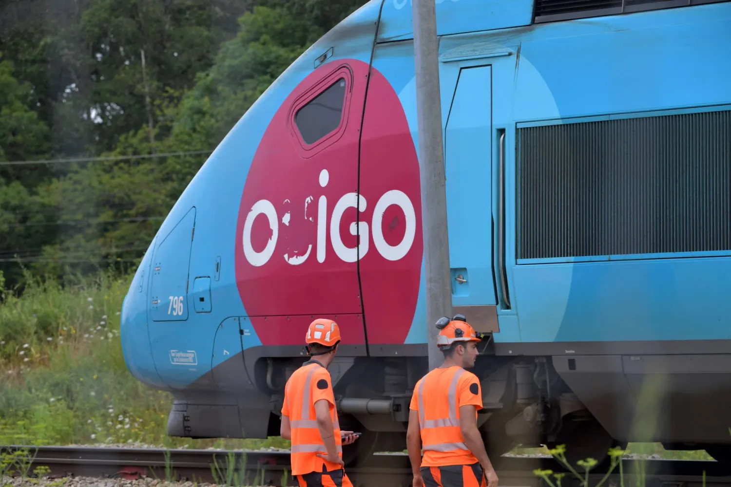 SNCF employees look on as a TGV train moves past them at Vald'yerre on the outskirts of Chartres, northern France on July 26, 2024, after the resumption of high speed train services on the line between Paris and Bordeaux. (Photo by JEAN-FRANCOIS MONIER / AFP)