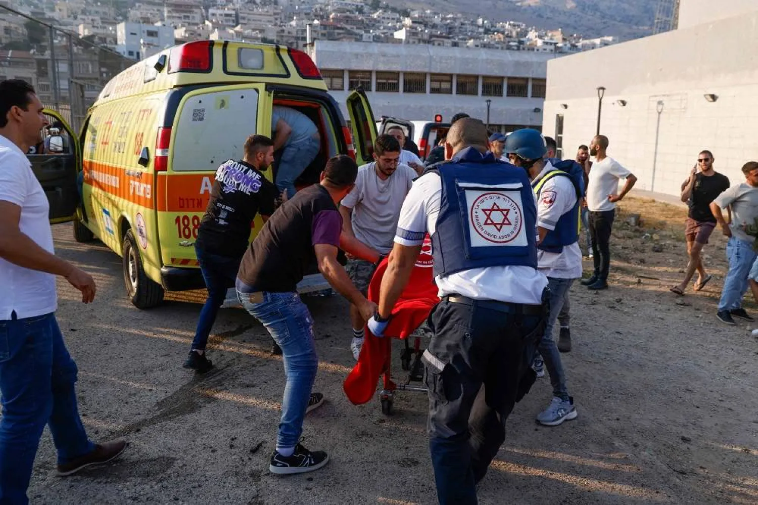 Israeli security forces and medics transport casualties along with local residents, at a site where a reported strike from Lebanon fell in Majdal Shams village in the Israeli-annexed Golan area on July 27, 2024. (AFP)
