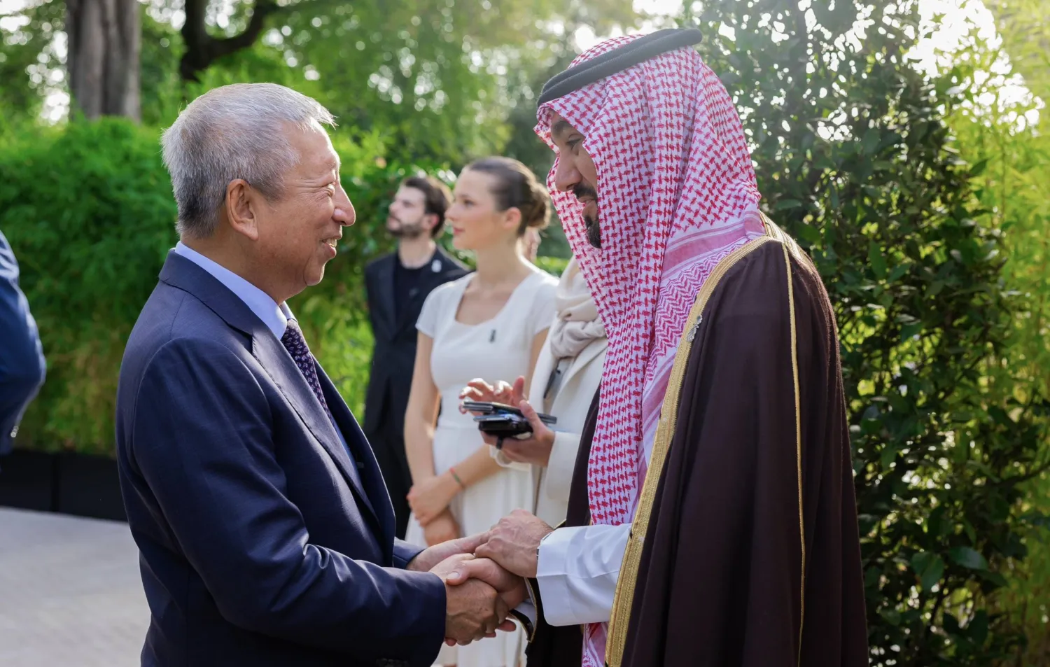 الفيصل لحظة استقباله أحد الضيوف الأولمبيين في الحفل السعودي (الأولمبية السعودية)