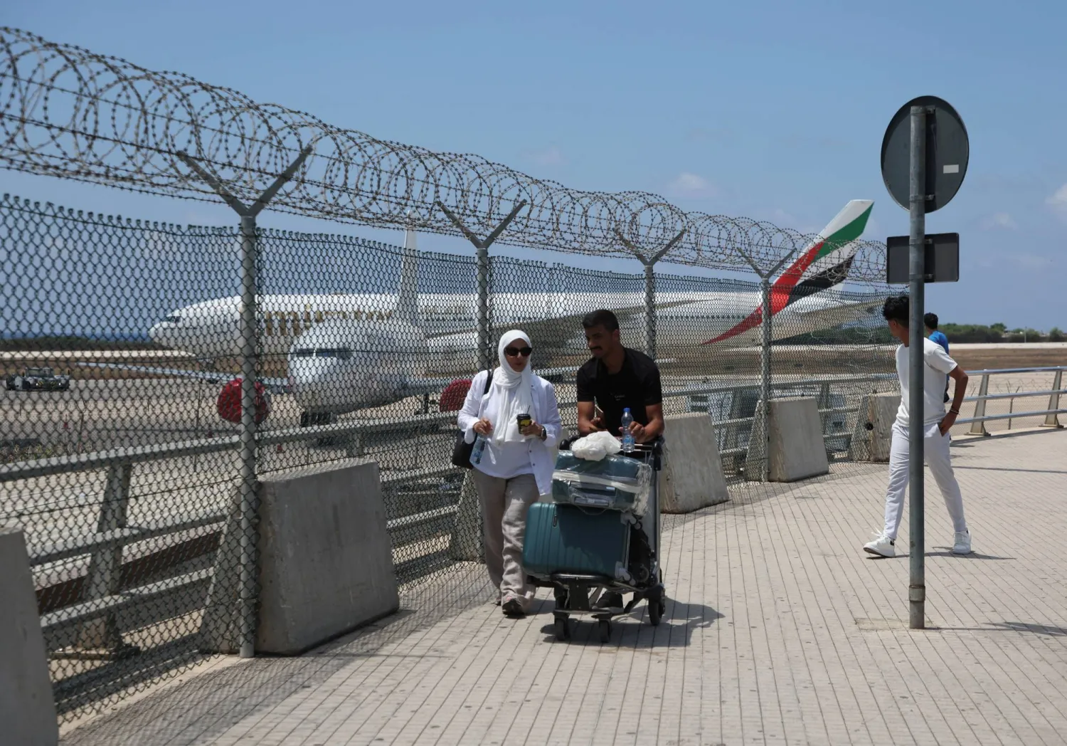 مسافران يدفعان بحقائبهما على مدخل مطار بيروت (رويترز)