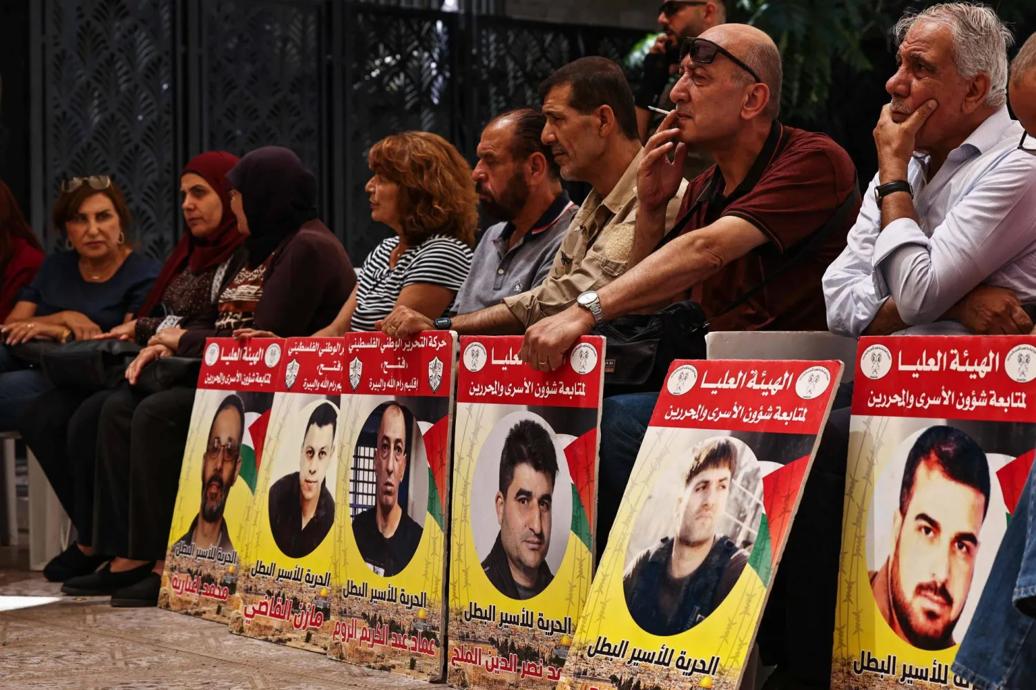 أشخاص يرفعون لافتات تحمل صور فلسطينيين معتقلين حالياً لدى إسرائيل خلال احتجاج تضامناً معهم ومع سكان قطاع غزة في مدينة رام الله بالضفة الغربية 30 يوليو 2024، وسط الصراع المستمر في غزة (أ.ف.ب)