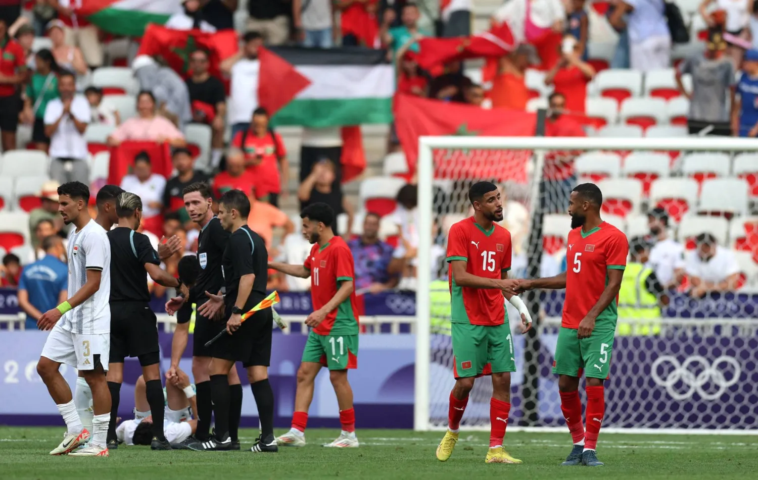 لاعبو المغرب يحتفلون بالفوز على العراق وتصدّر مجموعتهم بالأولمبياد (رويترز)