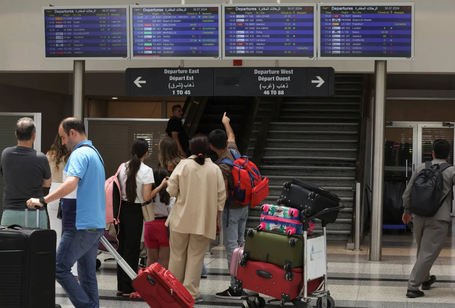 مسافرون يتفقّدون لوحات معلومات الرحلات داخل مطار رفيق الحريري الدولي في بيروت (رويترز)