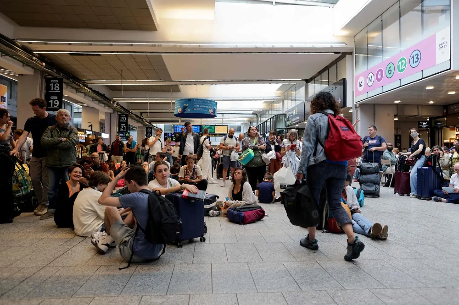 Passengers wait for their train departures at the Gare Montparnasse train station in Paris on July 26, 2024 as France's high-speed rail network was hit by malicious acts disrupting the transport system hours before the opening ceremony of the Paris 2024 Olympic Games. (AFP)