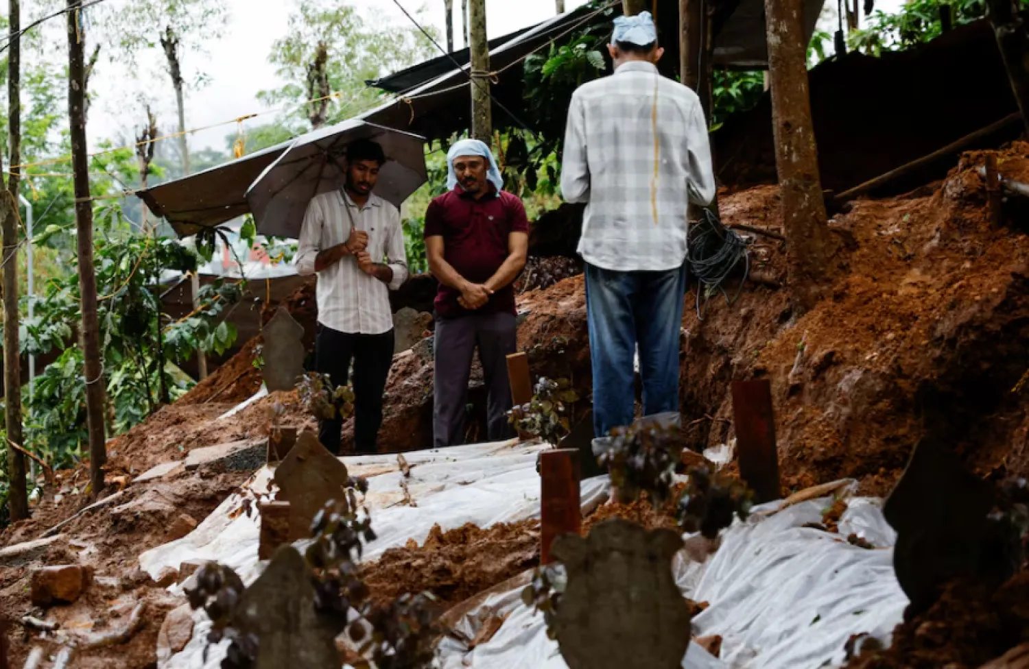 People pray for a departed family member at their grave at a graveyard, after landslides hit several villages in Wayanad district, in Meppadi, in the southern state of Kerala, India, August 2, 2024. REUTERS/Francis Mascarenhas Purchase Licensing Rights