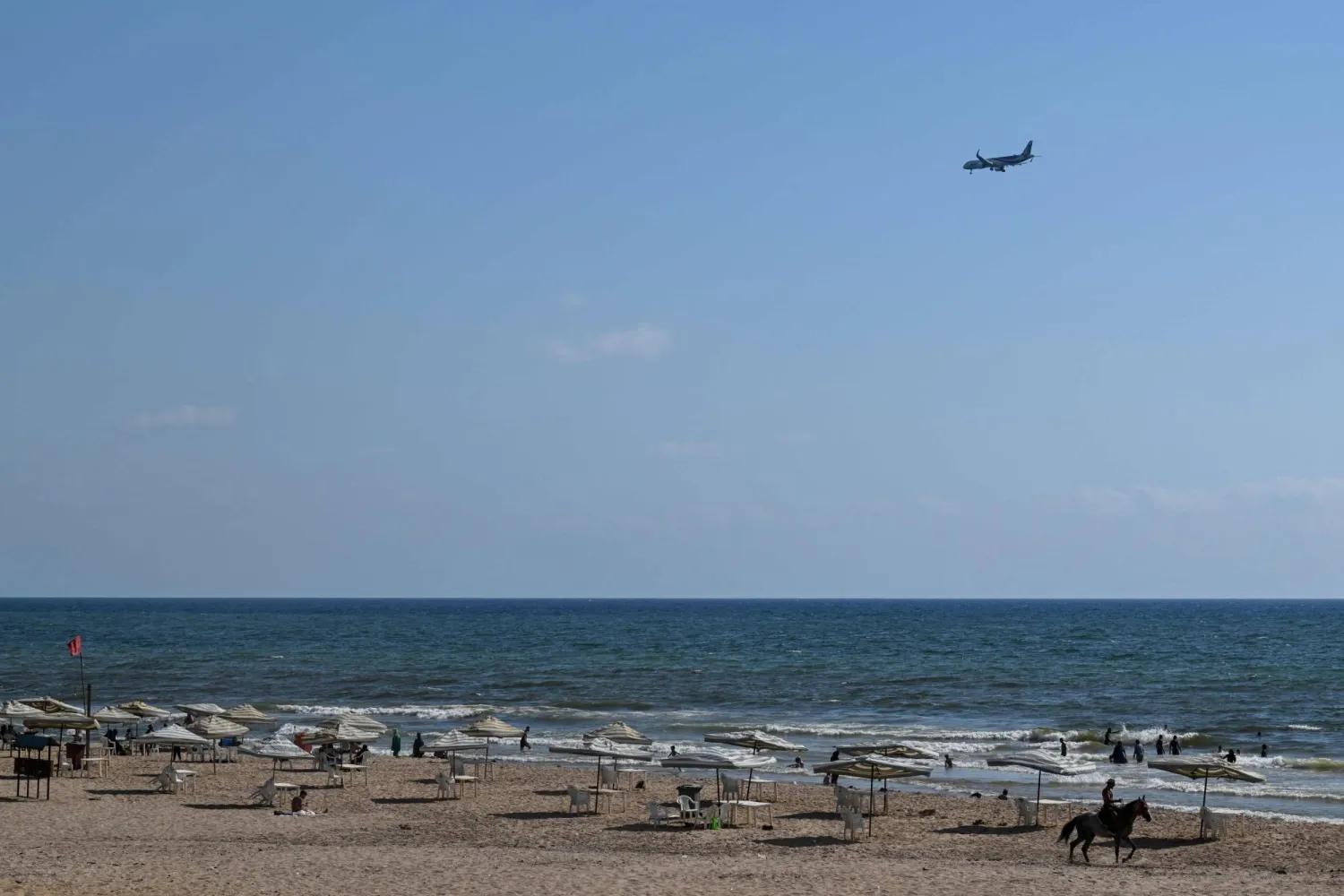 A Middle East Airlines plane flies over Beirut's Ramlet al-Baida beach as it approaches Beirut International Airport on August 2, 2024. (Photo by JOSEPH EID / AFP)