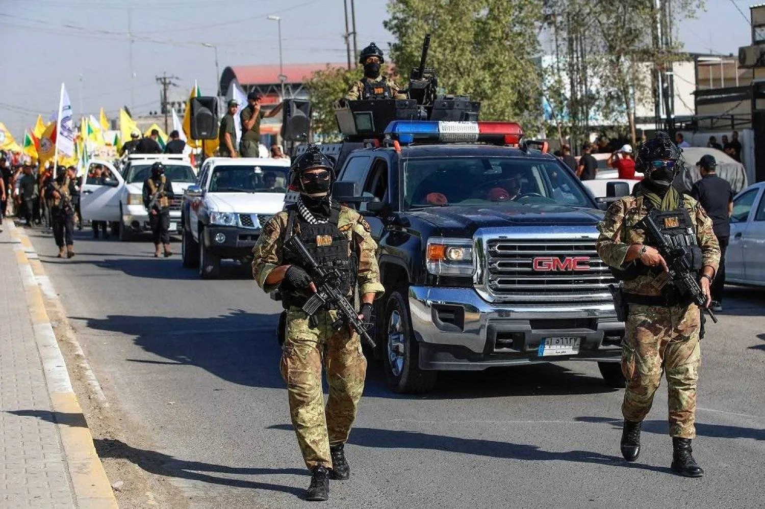 Supporters and members of Iraq's PMF wave flags as they march in Baghdad to condemn a US air strike in the south of the capital that killed four members of the Hashed, on July 31, 2024. (AFP)
