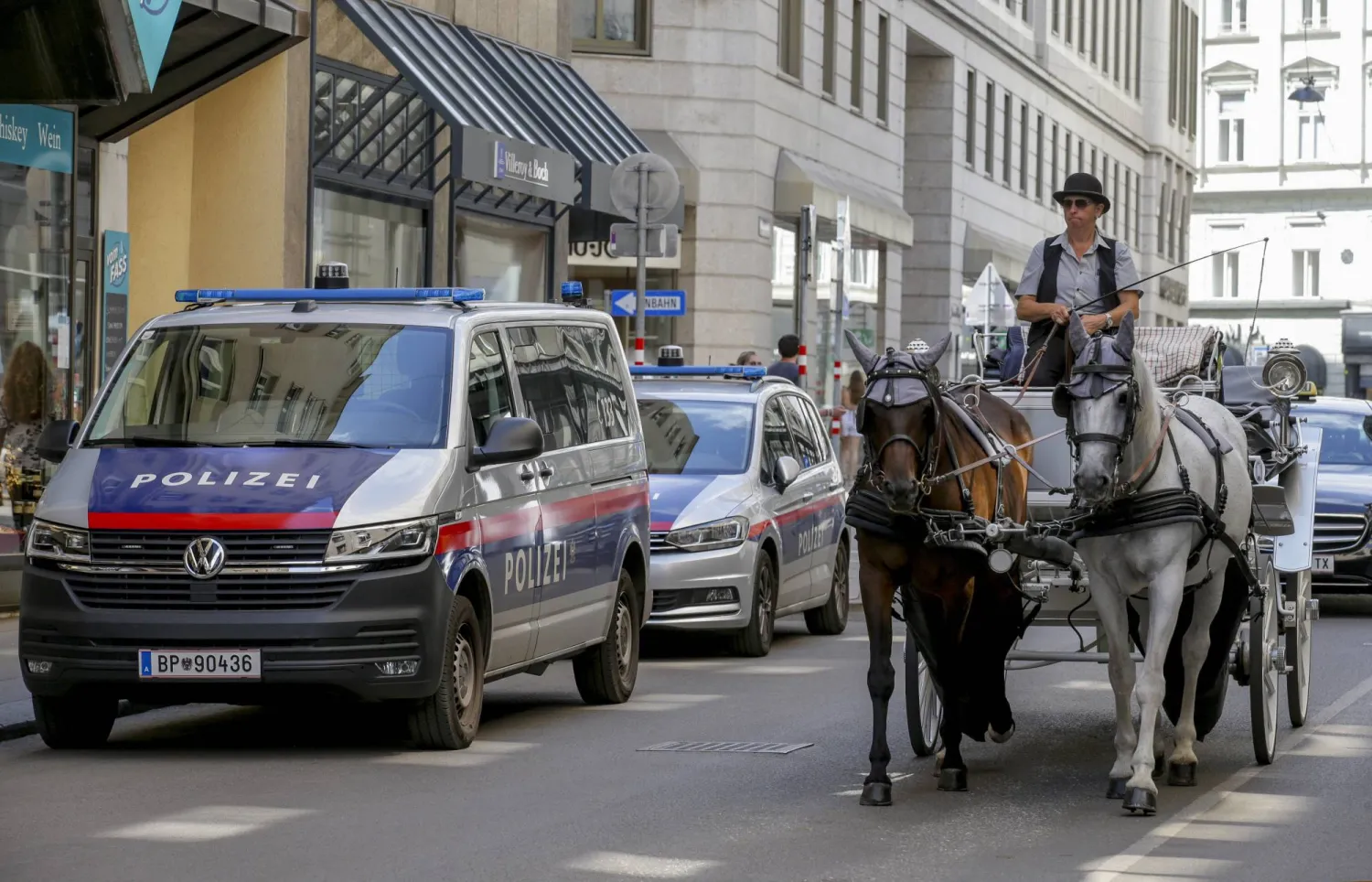 A carriage passes police cars in Vienna on Friday, Aug.9, 2024. (AP Photo/Heinz-Peter Bader)