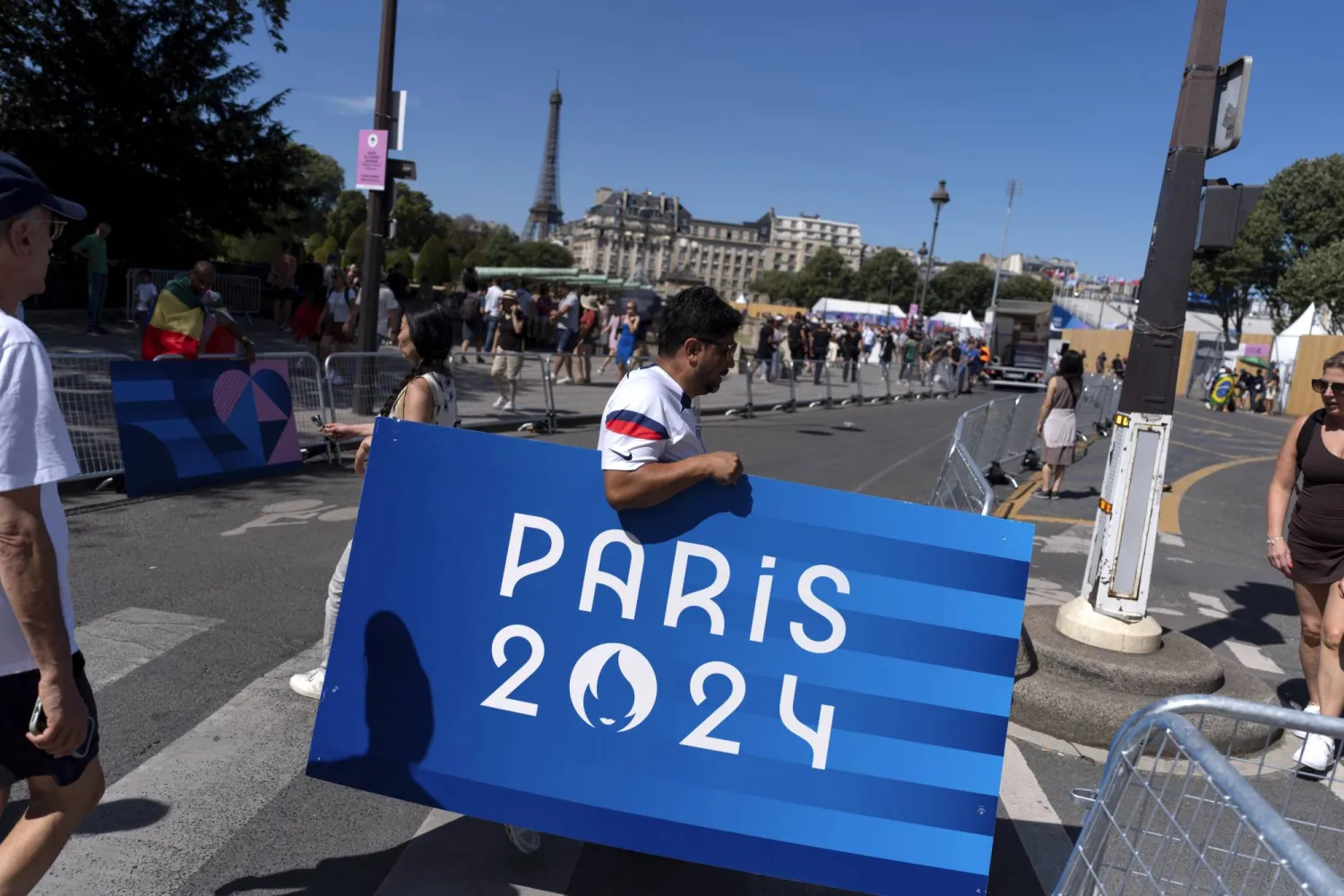 Spectators take home Olympic signage as the route for the women's marathon is broken down following its conclusion at the 2024 Summer Olympics, Sunday, Aug. 11, 2024, in Paris, France. (AP Photo/David Goldman)