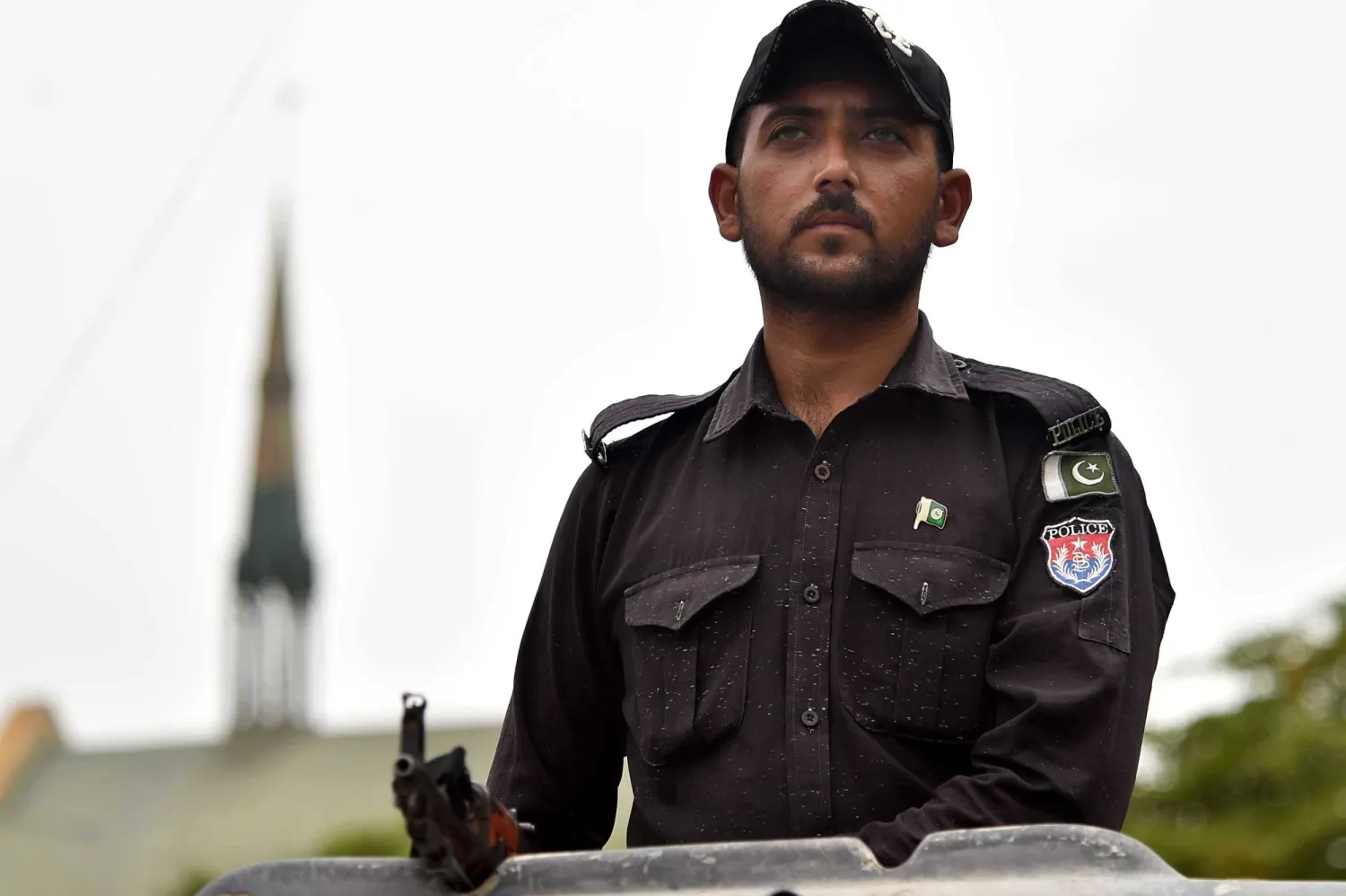 مسؤول أمني باكستاني يقف حراسة فيما يحتفل أفراد مجتمع الأقلية المسيحية الباكستانية بيوم الأقلية في كراتشي بباكستان الأحد (إ.ب.أ)