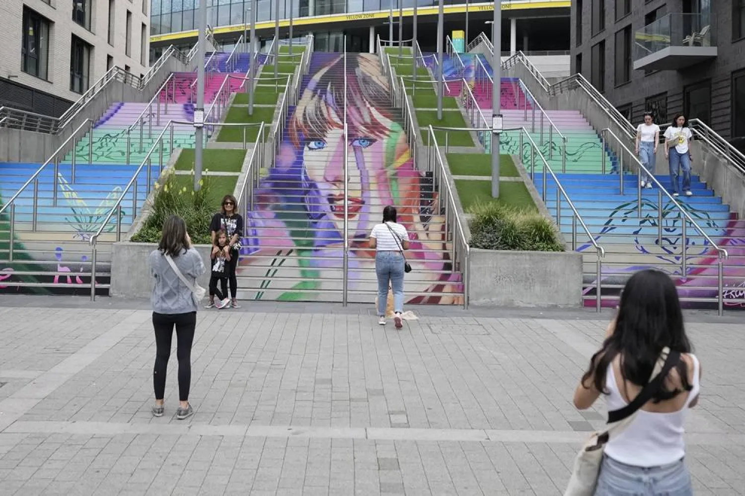  Fans pose by a Taylor Swift portrait painted on a stairway at Wembley Stadium in London, Wednesday, Aug. 14, 2024, ahead of a series of Taylor Swift concerts starting Thursday. (AP) 