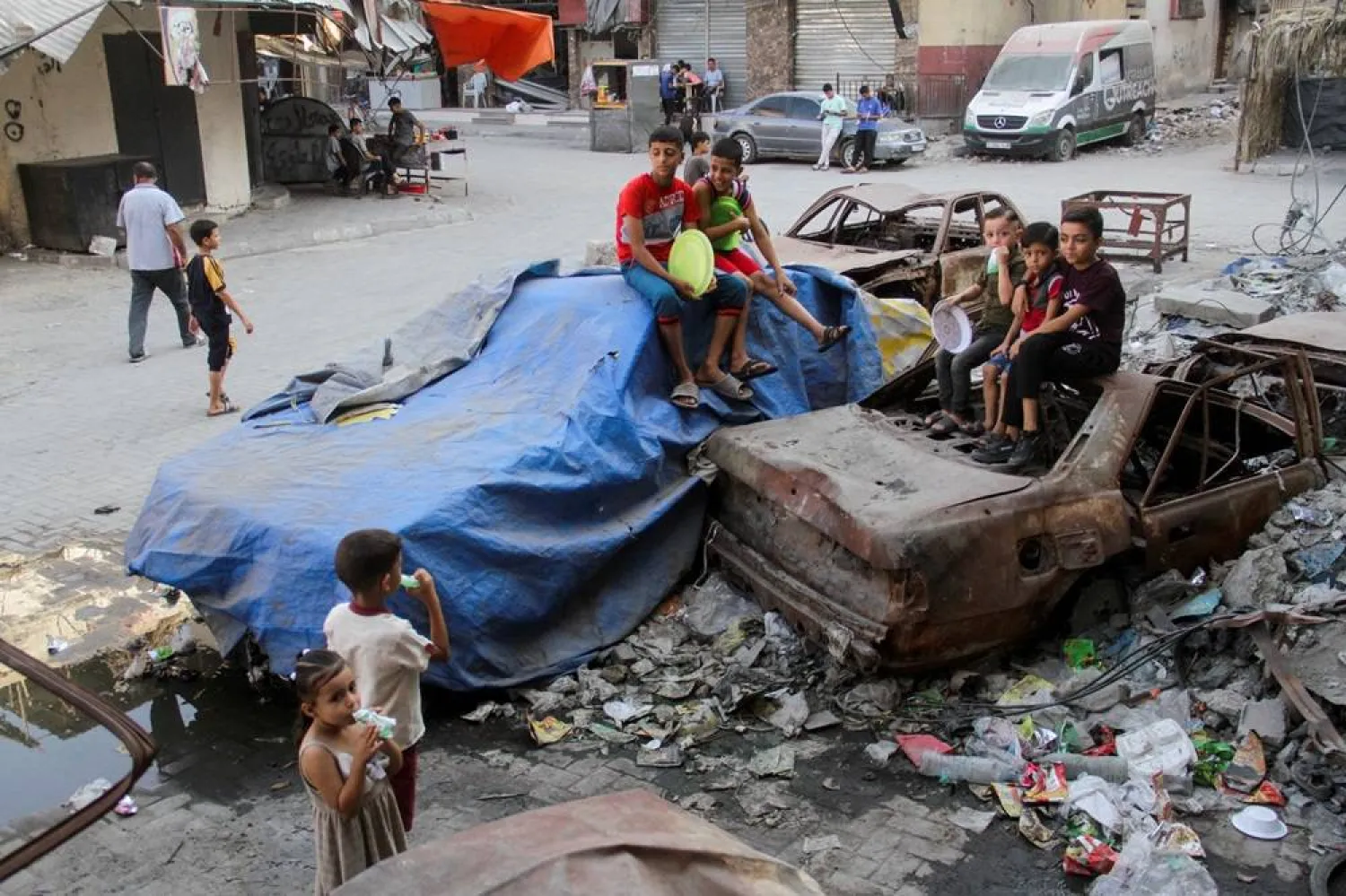  Children sit on damaged cars, as Palestinians wait to receive food cooked by a charity kitchen, amid a hunger crisis as conflict between Israel and Hamas continues, in the northern Gaza Strip August 14, 2024. (Reuters)