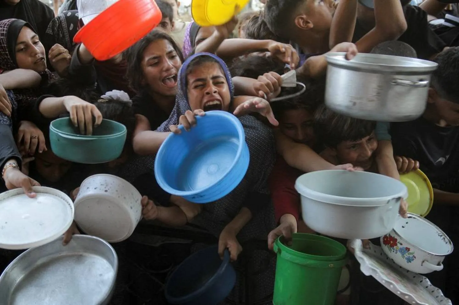  Palestinians react as they wait to receive food cooked by a charity kitchen, amid a hunger crisis as conflict between Israel and Hamas continues, in the northern Gaza Strip August 14, 2024. (Reuters)