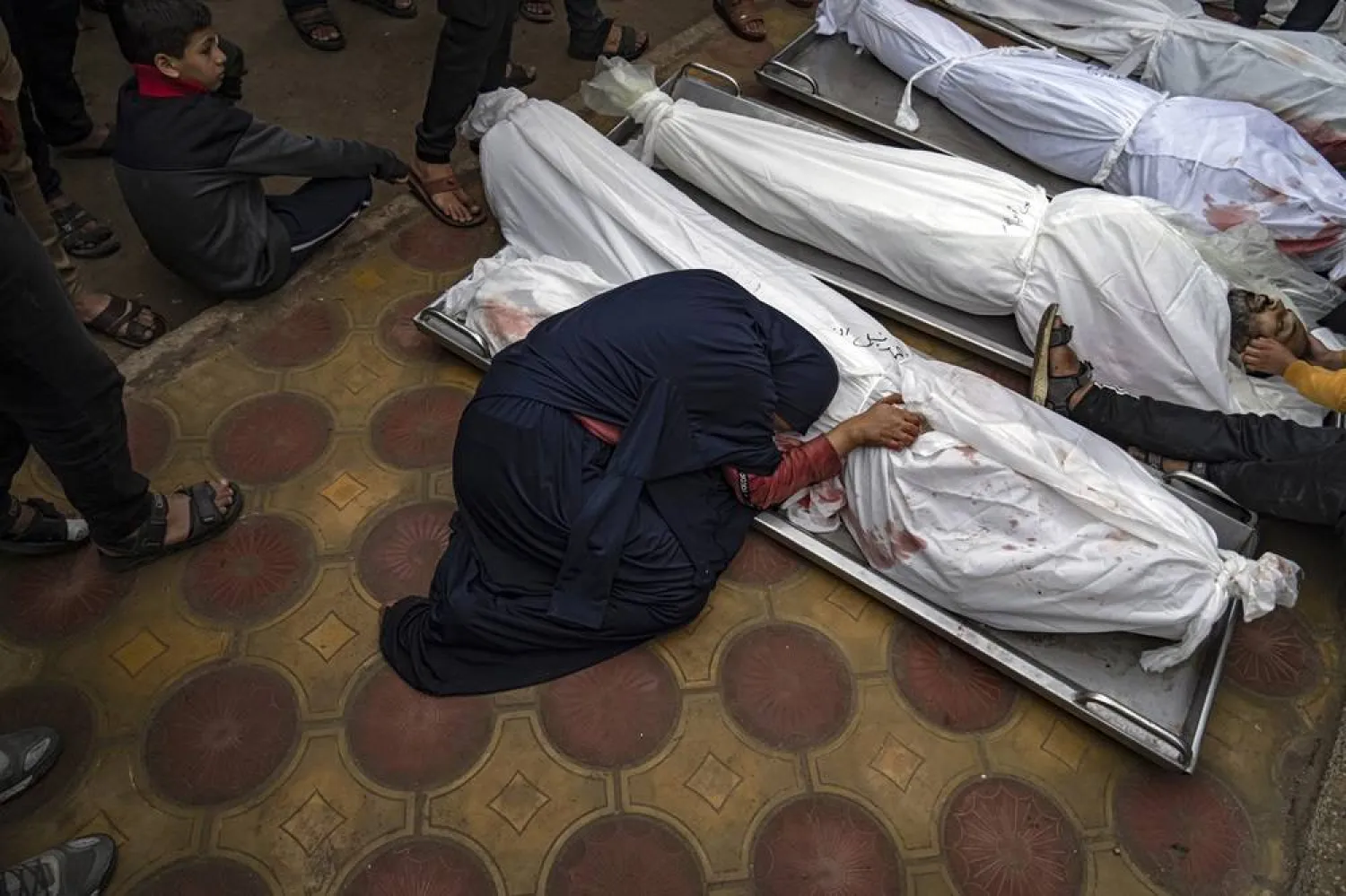 A woman mourns the covered bodies of her child and her husband killed in an Israeli army bombardment of the Gaza Strip, in the hospital in Khan Younis, Tuesday Dec. 5, 2023. (AP)