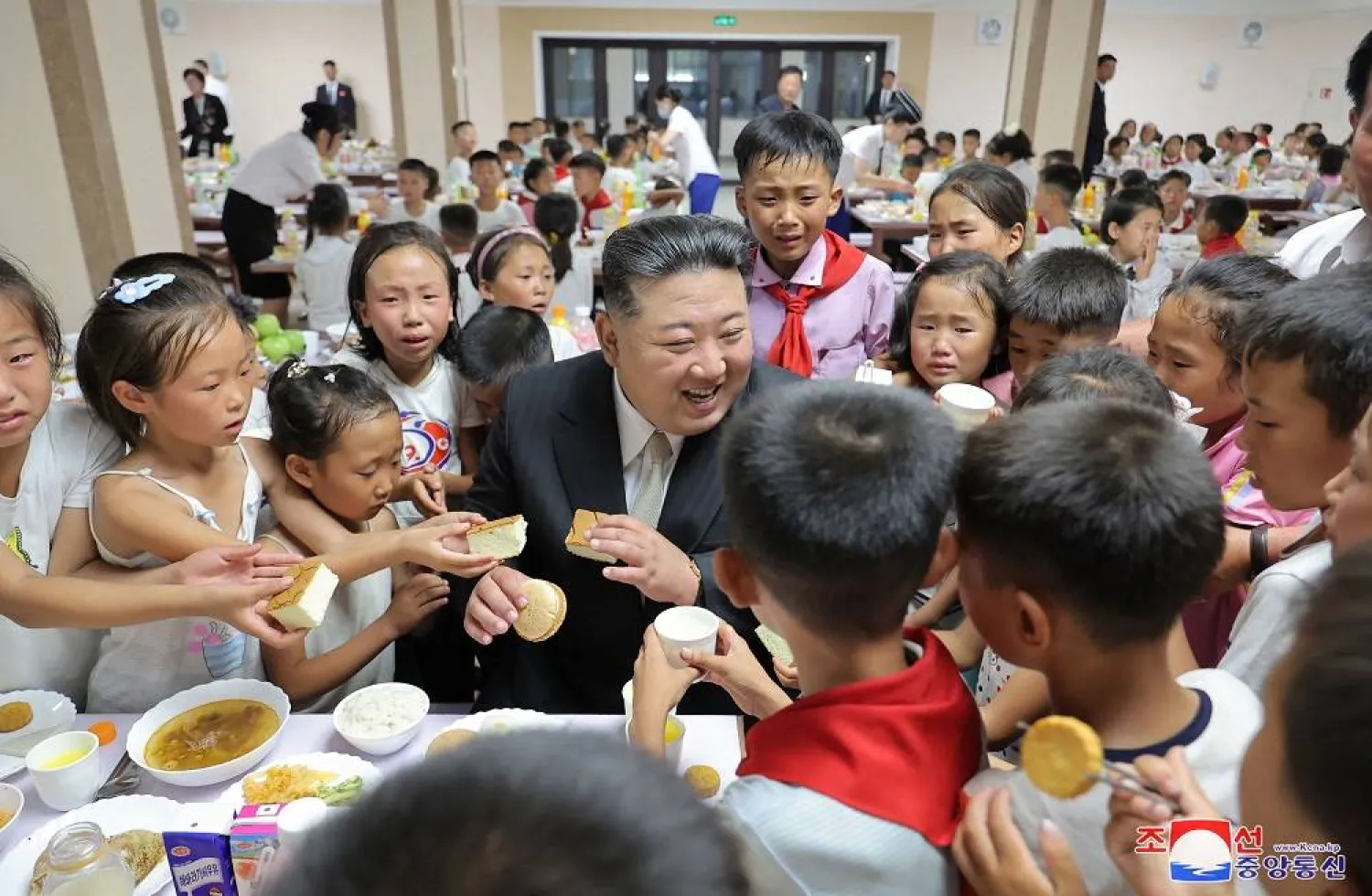 This picture taken on August 15, 2024 and released from North Korea's official Korean Central News Agency (KCNA) via KNS on August 16, 2024 shows North Korea's leader Kim Jong Un (C) visiting the children of flood-affected victims, who were relocated from the northwestern part of the country, as they eat at a dining hall in Pyongyang.  (KCNA via KNS / AFP)