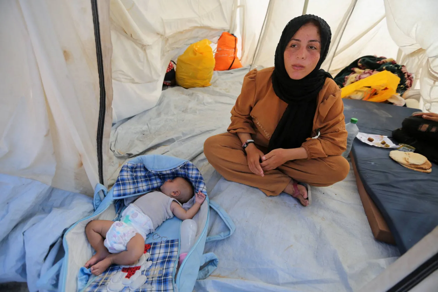 نازحة فلسطينية لجأت إلى المقابر في خان يونس مع طفلها (رويترز)