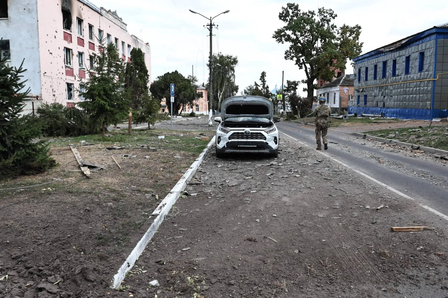 This photograph taken on 16 August, 2024, a media tour organized by Ukraine, shows a Ukrainian soldier walking on a damaged street in Ukrainian-controlled Russian town of Sudzha, Kursk region, amid the Russian invasion in Ukraine. (Photo by Yan DOBRONOSOV / AFP)