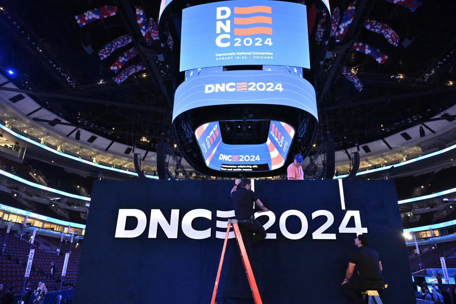 Workers install a sign as preparations continue one day ahead of the Democratic National Convention (DNC) at the United Center in Chicago, Illinois, on August 18, 2024. (Photo by ANDREW CABALLERO-REYNOLDS / AFP)