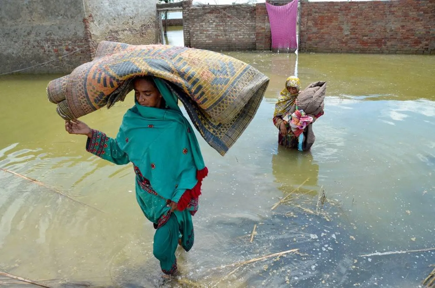  A family displaced by flood, carry their belongings as they wade through floodwaters after heavy monsoon rains at Sohbatpur in Jaffarabad district, Balochistan province on August 19, 2024. (AFP)