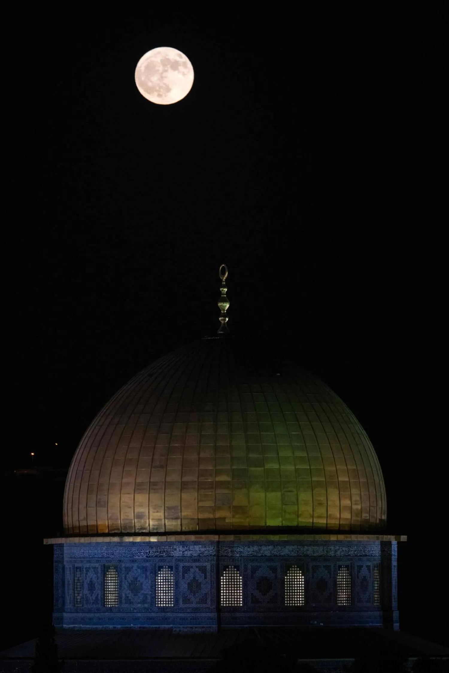 القمر الأزرق العملاق يظهر خلف مسجد قبة الصخرة في مجمع المسجد الأقصى بالقدس (أ.ف.ب)