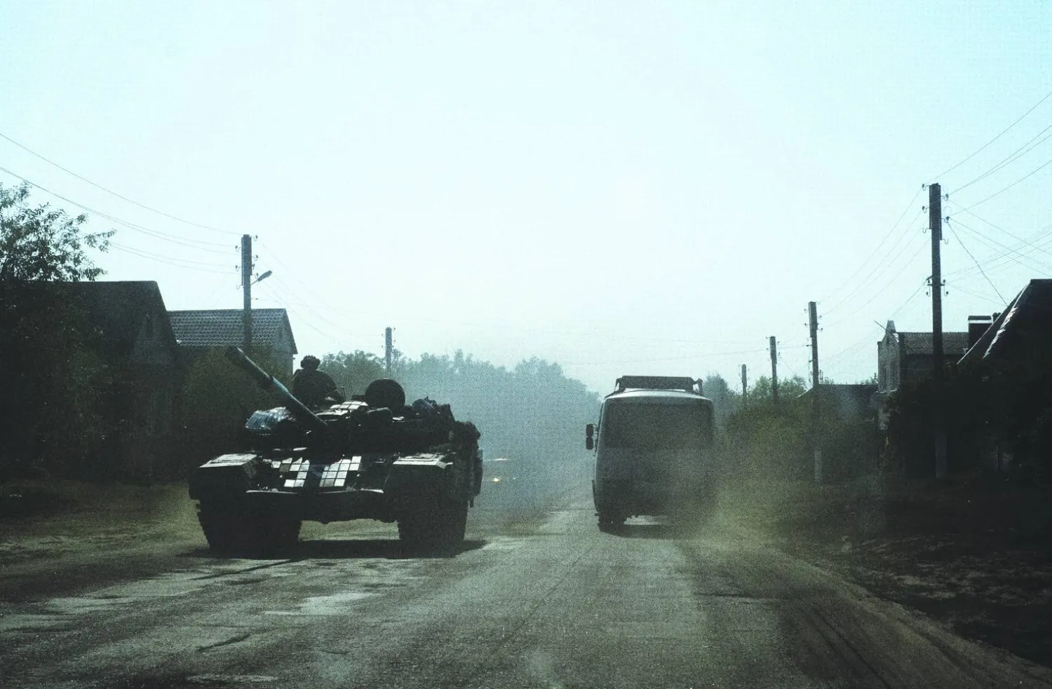 
حافلة مدنية تمرّ بجوار دبابة أوكرانية قرب الحدود الروسية الأحد (إ.ب.أ)