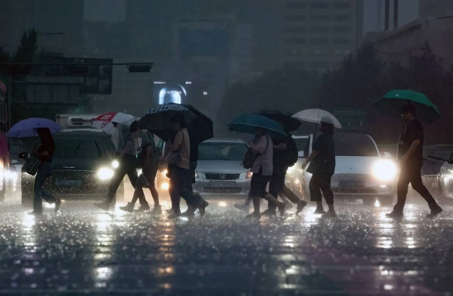 People walk across a crosswalk in downtown Seoul on a rainy morning, South Korea 21 August 2024, following the arrival of the weakened Typhoon Jongdari. (EPA/Yonhap)