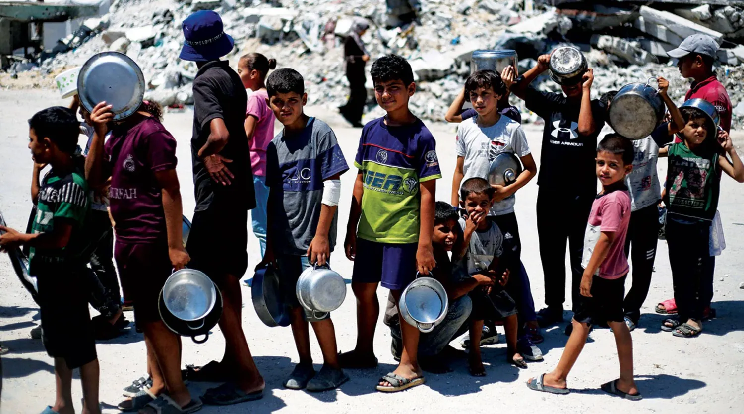 أطفال فلسطينيون في مخيم البريج بقطاع غزة أمس ينتظرون وجبة طعام (أ.ف.ب)
