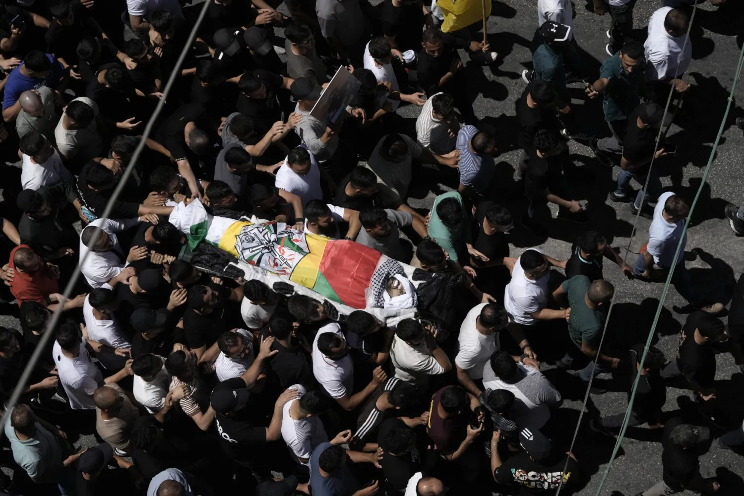 يحمل المشيعون جثمان شاب فلسطيني قتل في اشتباكات مع القوات الإسرائيلية بالضفة الغربية (أ.ب)