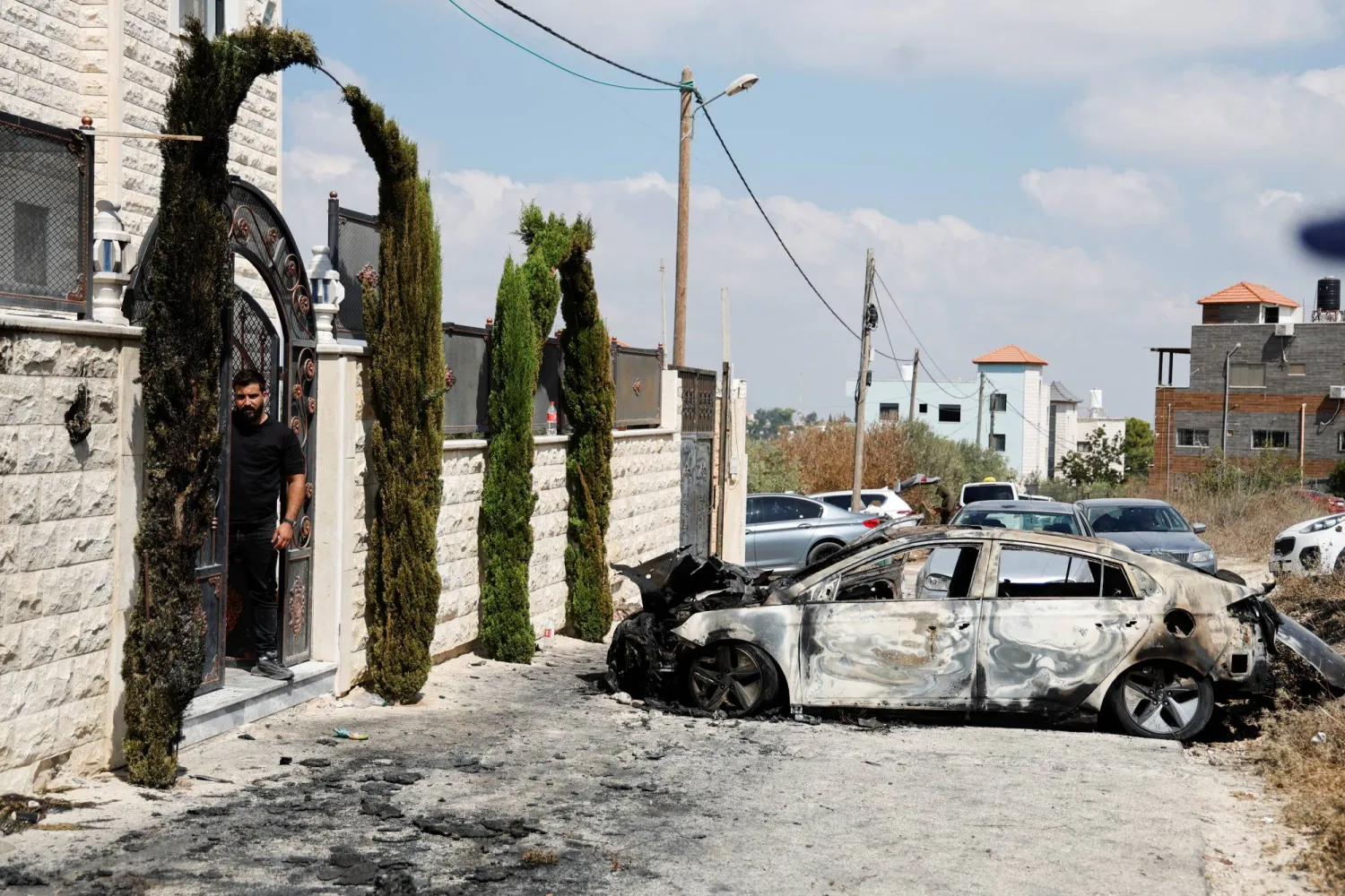 A Palestinian man stands near a vehicle destroyed during an Israeli settlers' attack in the village of Jeit, near Qalqilya in the Israeli-occupied West Bank August 16, 2024. REUTERS/Raneen Sawafta