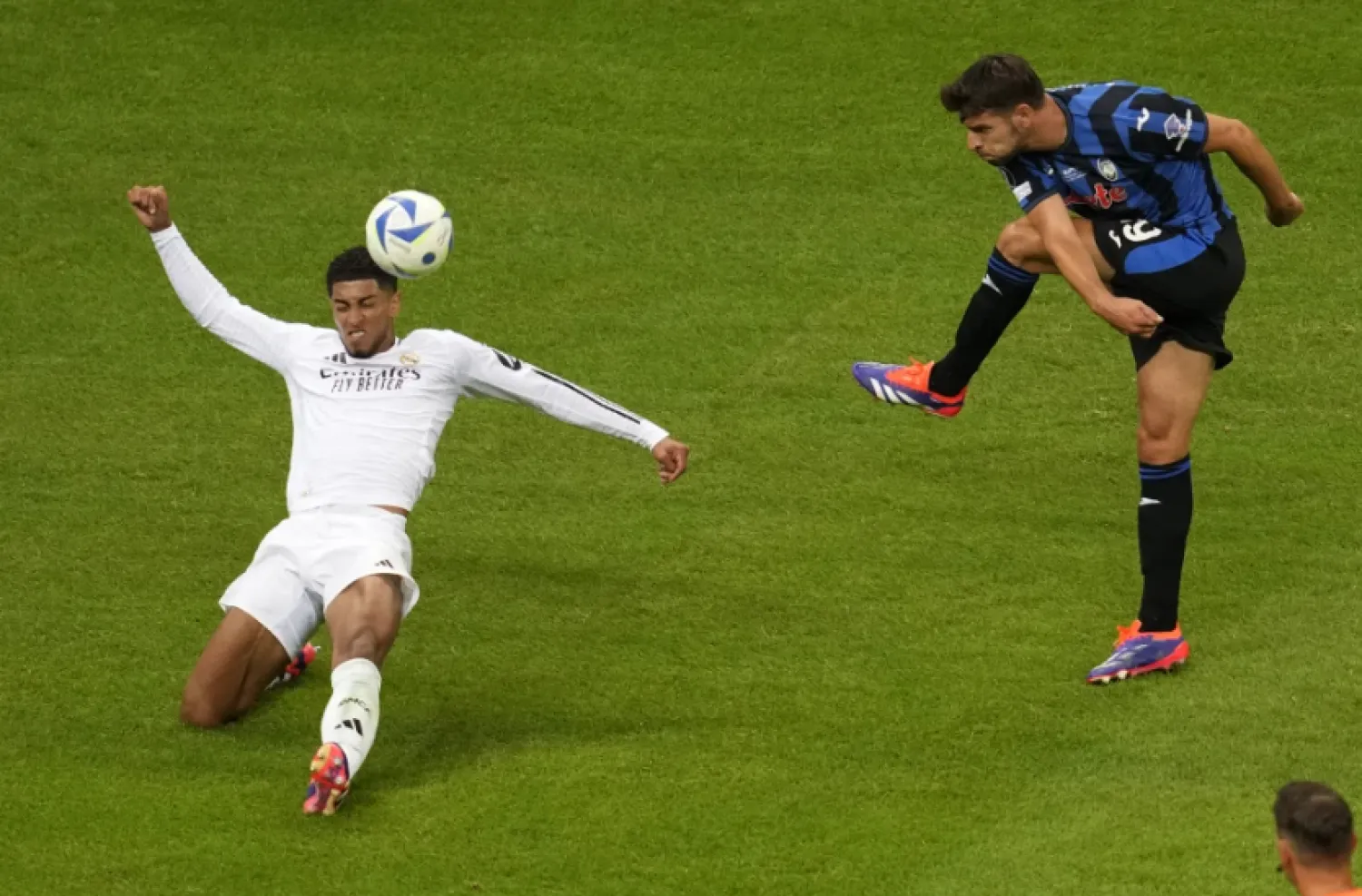 Atalanta’s Berat Djimsiti, right, attempts a shot at goal in front of Real Madrid’s Jude Bellingham during the UEFA Super Cup Final soccer match between Real Madrid and Atalanta at the Narodowy stadium in Warsaw, Poland, Wednesday, Aug. 14, 2024. (AP Photo/Darko Vojinovic)

