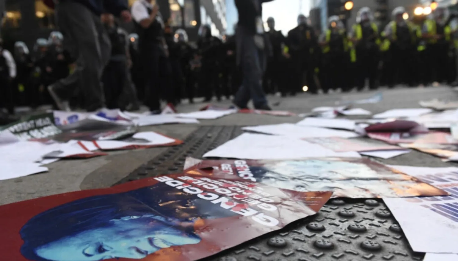An image of Kamala Harris with the word "Genocide" written is left on the pavement as police officers line up during a protest as the Democratic National Convention (DNC) takes place in Chicago, Illinois, on August 20, 2024. © Matthew Hatcher, AFP
