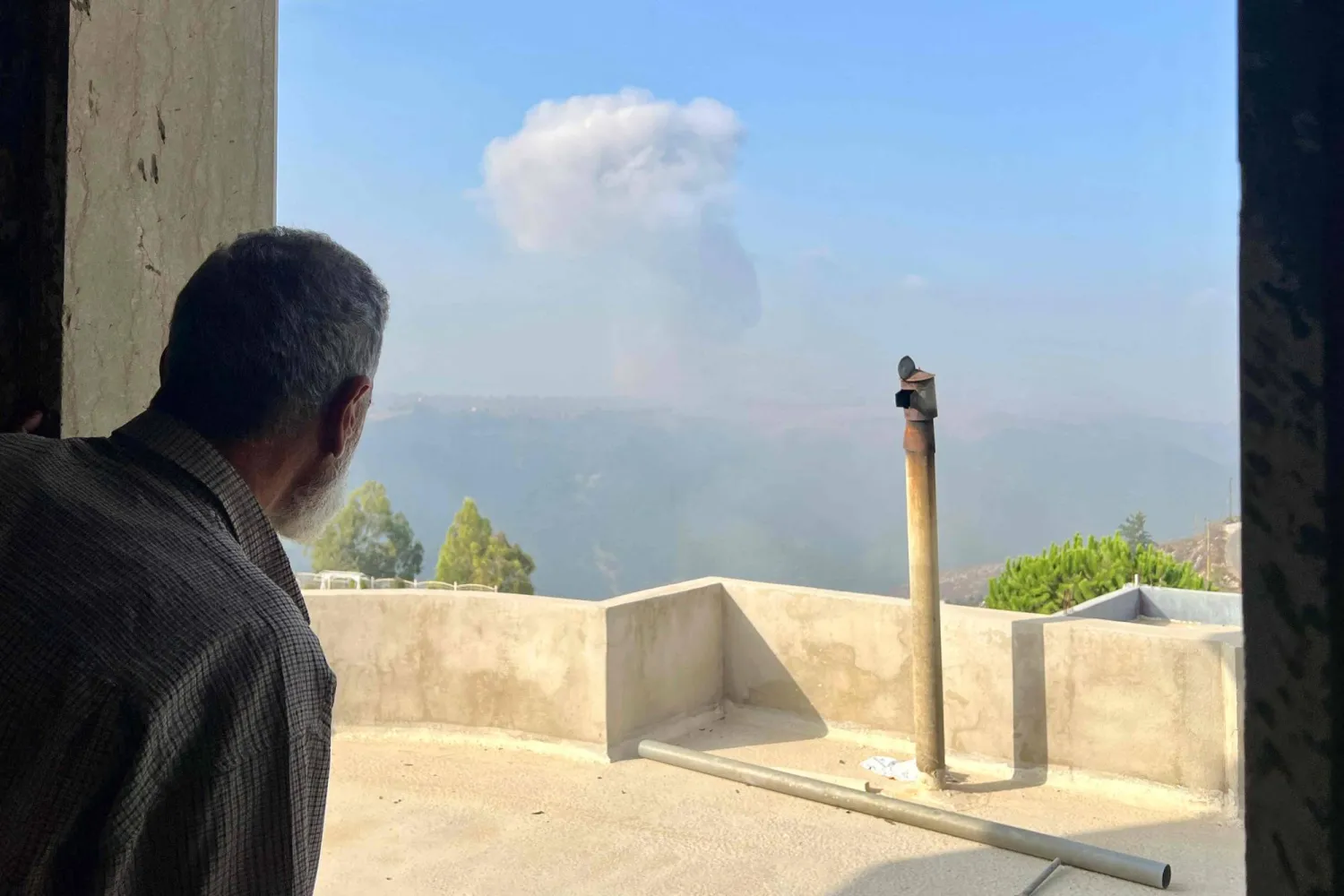 A man watches smoke billow after an Israeli airstrike in the southern Lebanese village of Qsair on August 25, 2024. (Photo by AFP)