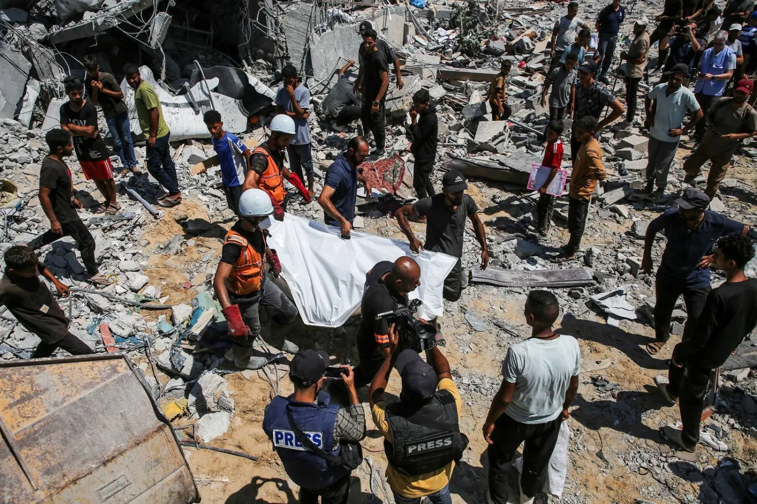 يحملون جثة في أثناء تفقُّدهم الأضرار عقب غارة إسرائيلية في خان يونس (رويترز)