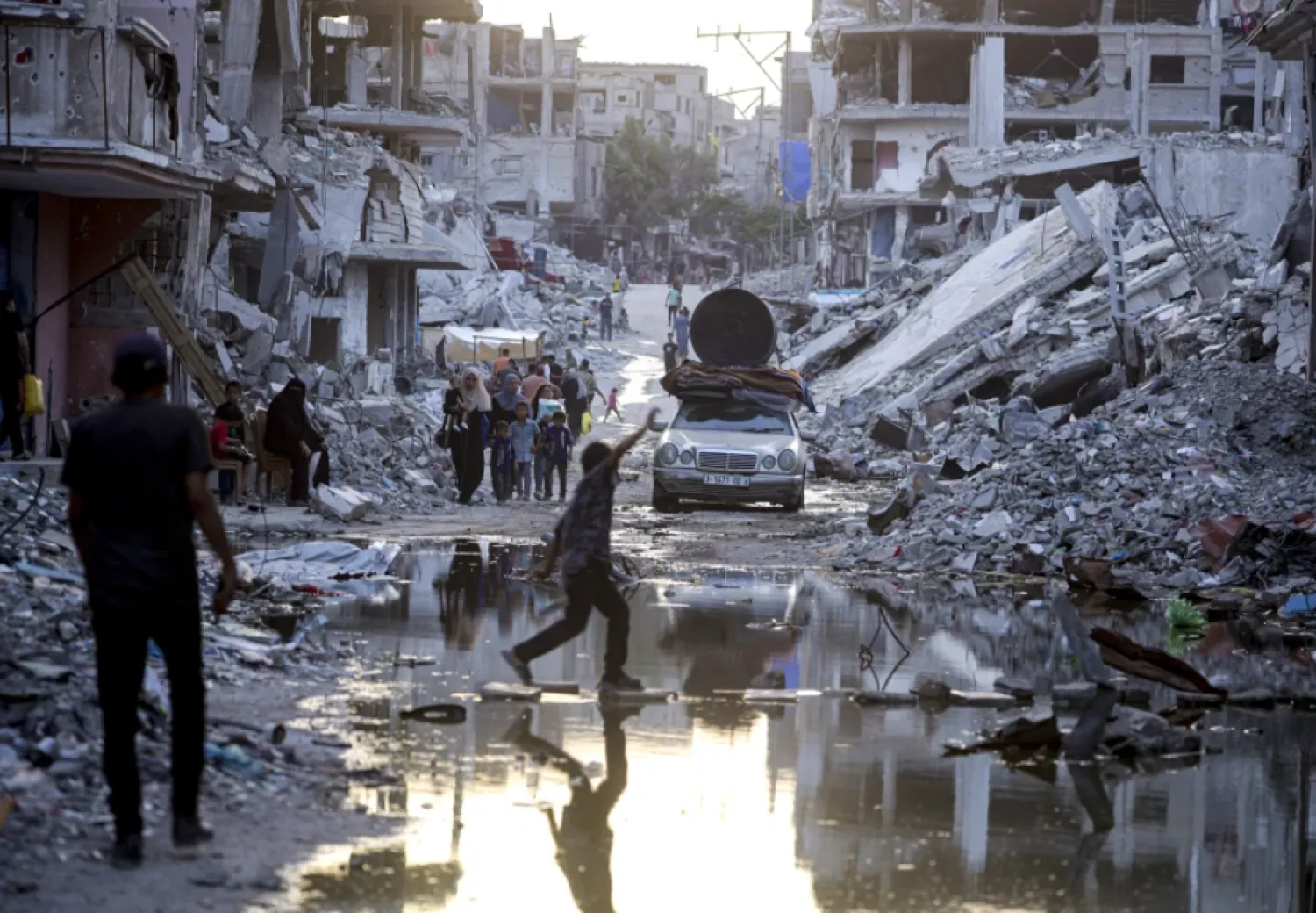 FILE - Palestinians displaced by the Israeli air and ground offensive on the Gaza Strip, walk past sewage flowing into the streets of the southern town of Khan Younis, Gaza Strip, on July 4, 2024. Israel’s military on Sunday Aug. 25, 2024 said polio vaccines for more than 1 million people had been delivered to Gaza, after the first confirmed case of the disease in the territory in a quarter-century. (AP Photo/Jehad Alshrafi, File)

