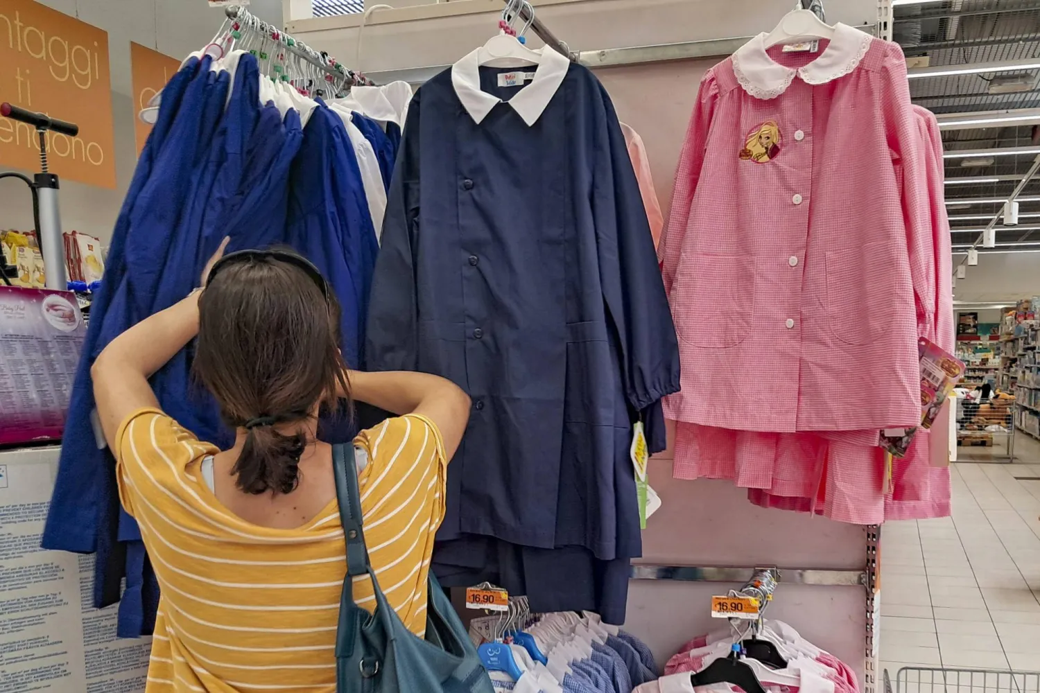 سيدة تبحث في متجر خاص بالزي المدرسي في روما (إ.ب.أ)