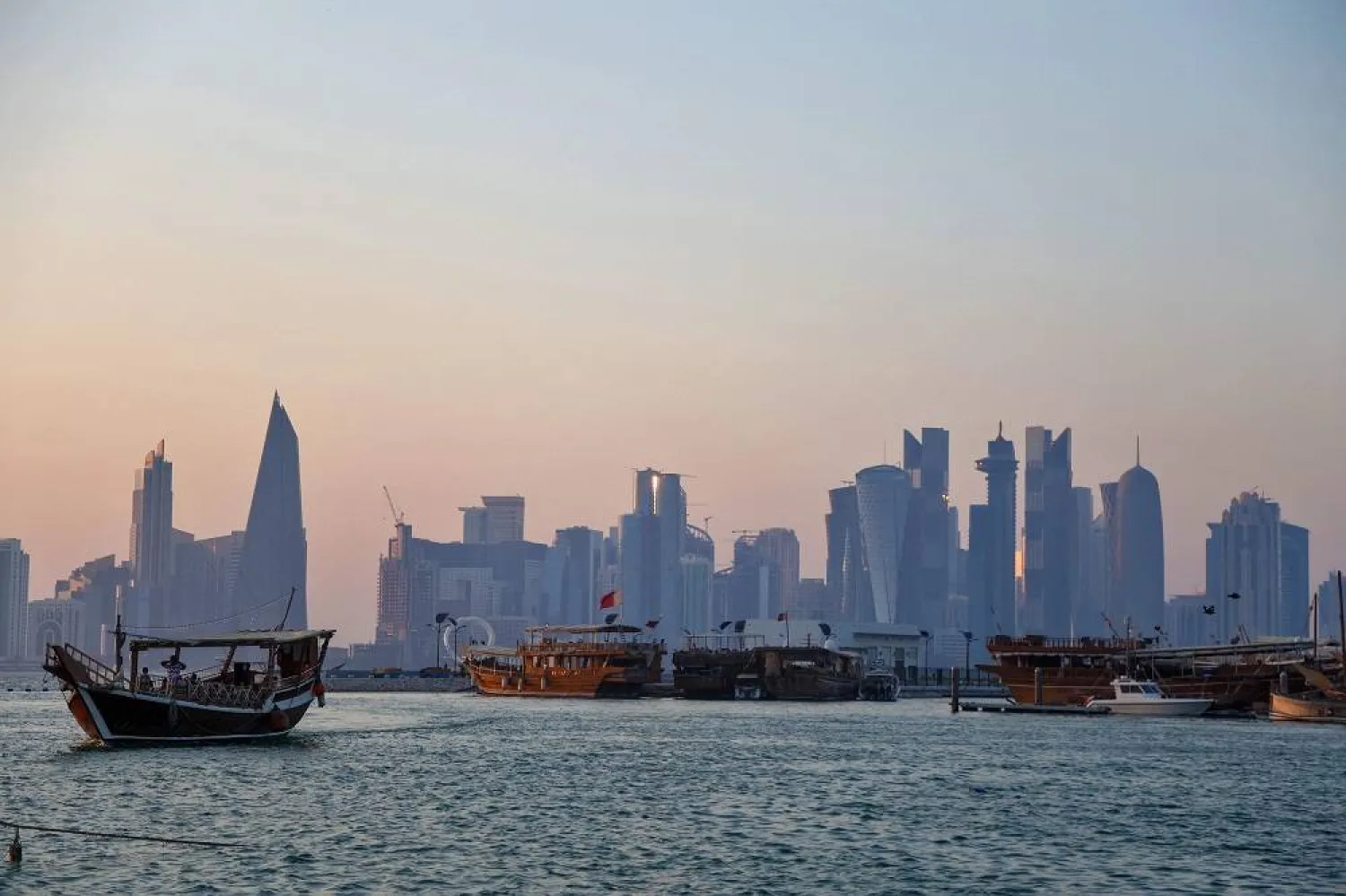 This picture taken from Doha's seaside promenade shows traditional Qatari Dhow boats with the Qatari capital's skyline seen in the background on August 16, 2024. (AFP)