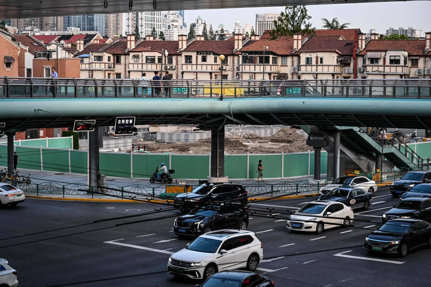 سيارات تمر أسفل كوبري مشاة في مدينة شنغهاي الصينية (أ.ف.ب)