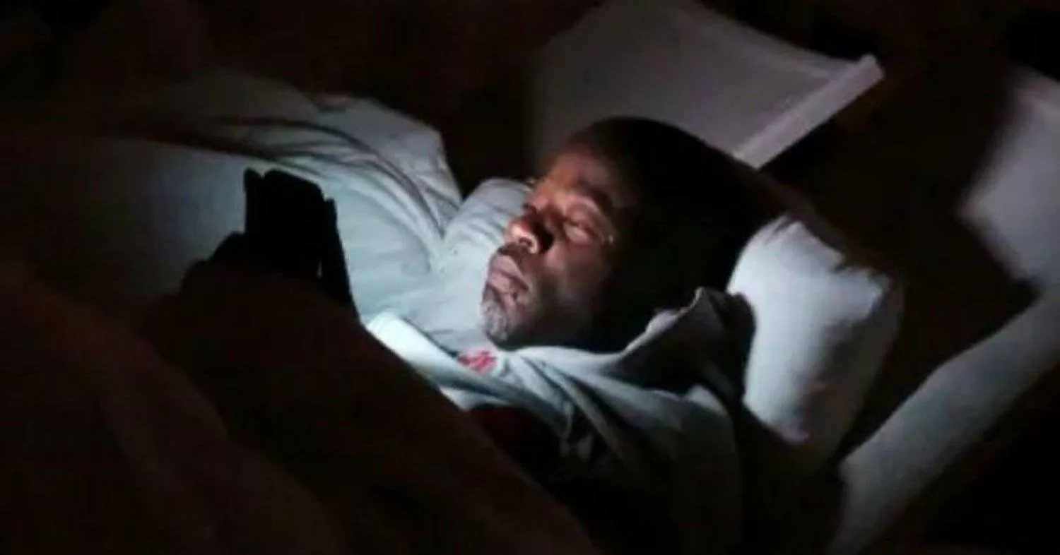 رجل يستخدم هاتفه بينما يستلقي في الفراش (أرشيف - رويترز)