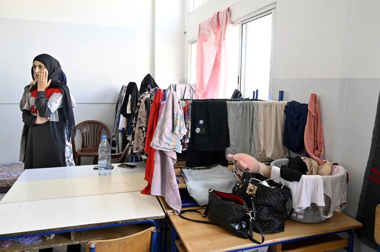 نازحات من جنوب لبنان يقفن في صف إحدى المدارس المحلية التي تُستخدم مأوىً بمدينة صور الساحلية جنوب لبنان (إ.ب.أ)