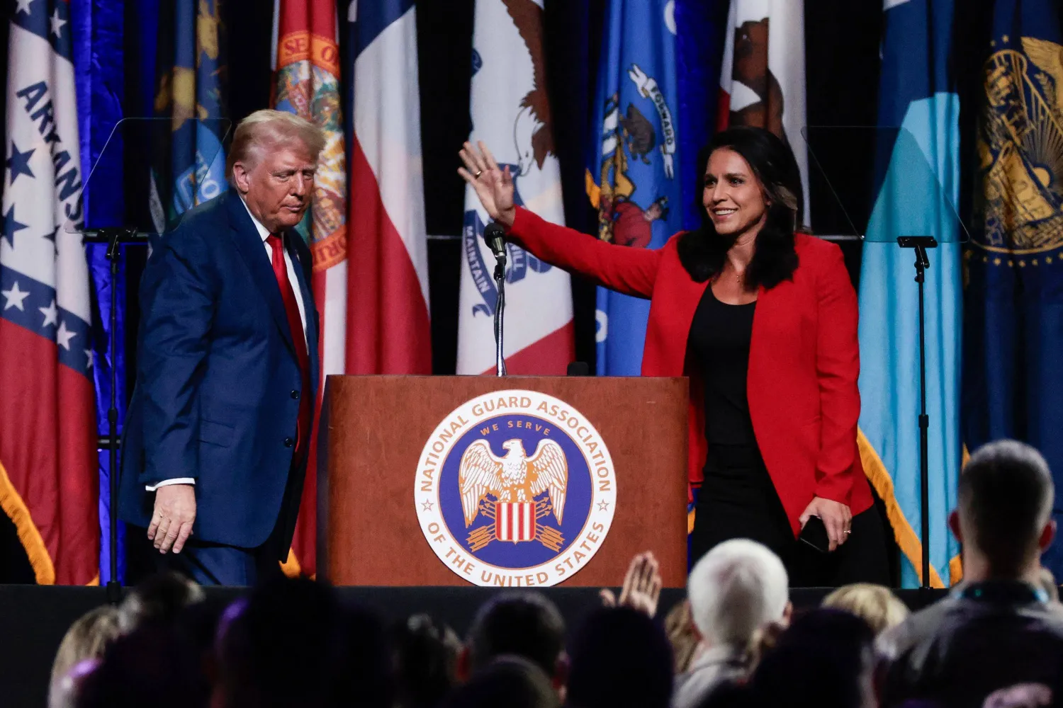 Former US Representative Tulsi Gabbard (R) waves after endorsing former US President and 2024 Republican presidential candidate Donald Trump (L) at the National Guard Association conference in Detroit, Michigan, on August 26, 2024. (Photo by JEFF KOWALSKY / AFP)