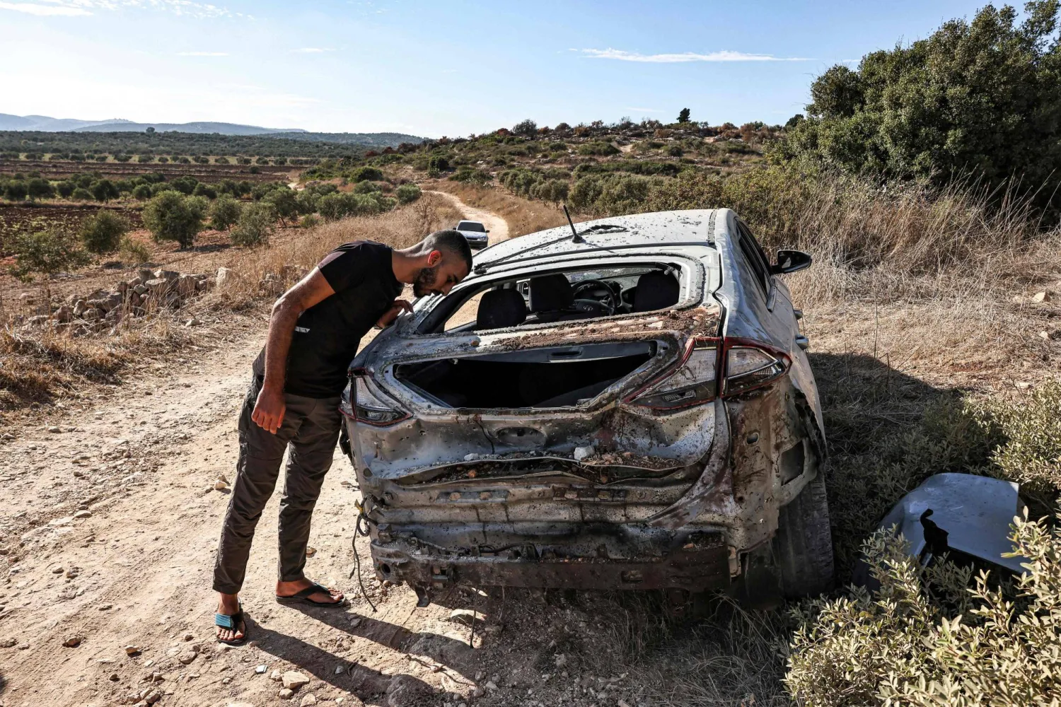رجل يتفقد مركبة مدمرة بعد مداهمة للجيش الإسرائيلي على طريق بين جنين وطوباس شمال الضفة الغربية (أ.ف.ب)
