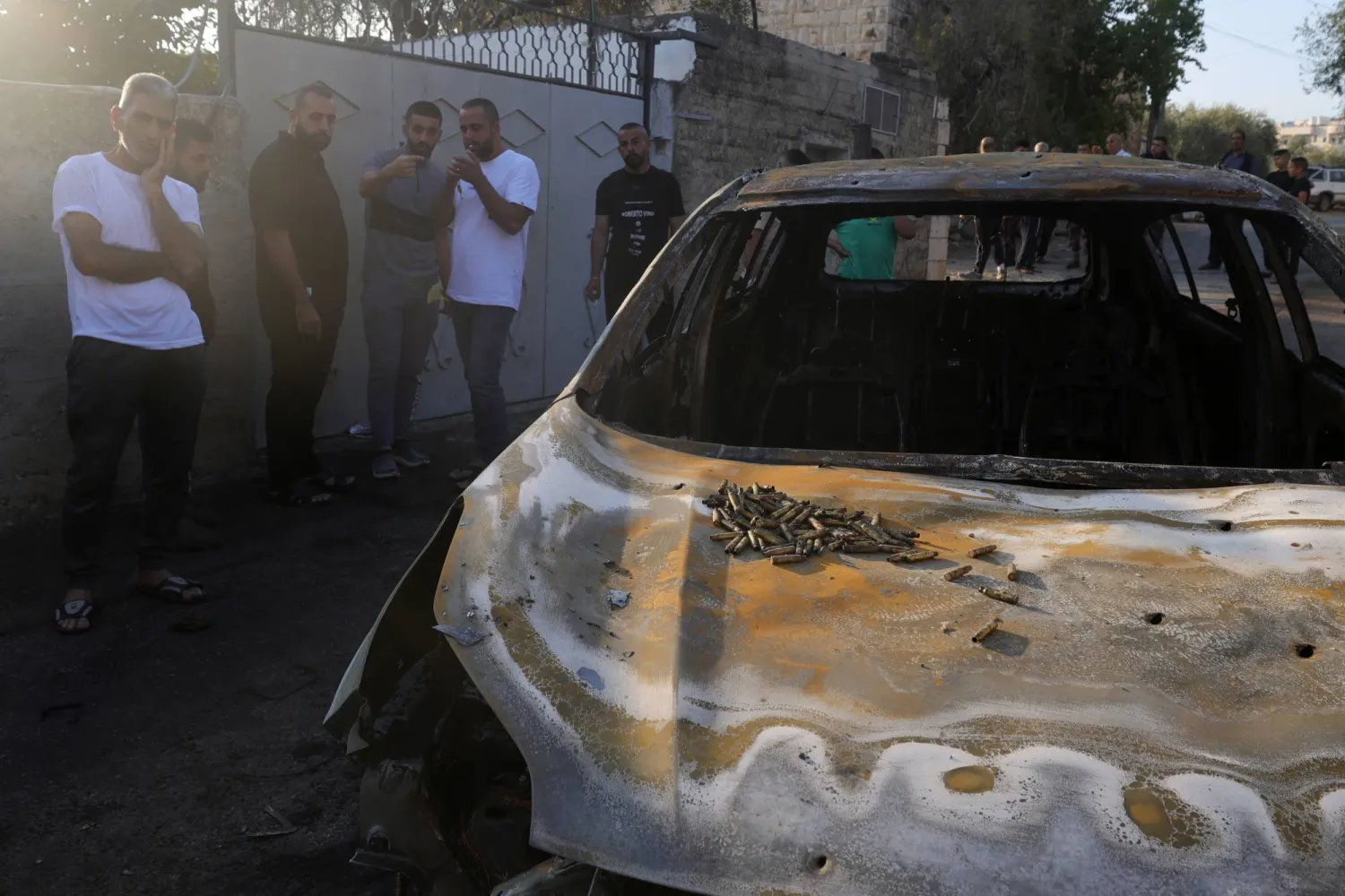 فلسطينيون يتفقدون سيارة دمّرتها غارة جوية في قرية الزبابدة قرب مدينة جنين بالضفة الغربية... 30 أغسطس 2024 خلال اليوم الثالث من العملية العسكرية الإسرائيلية في المنطقة (إ.ب.أ)