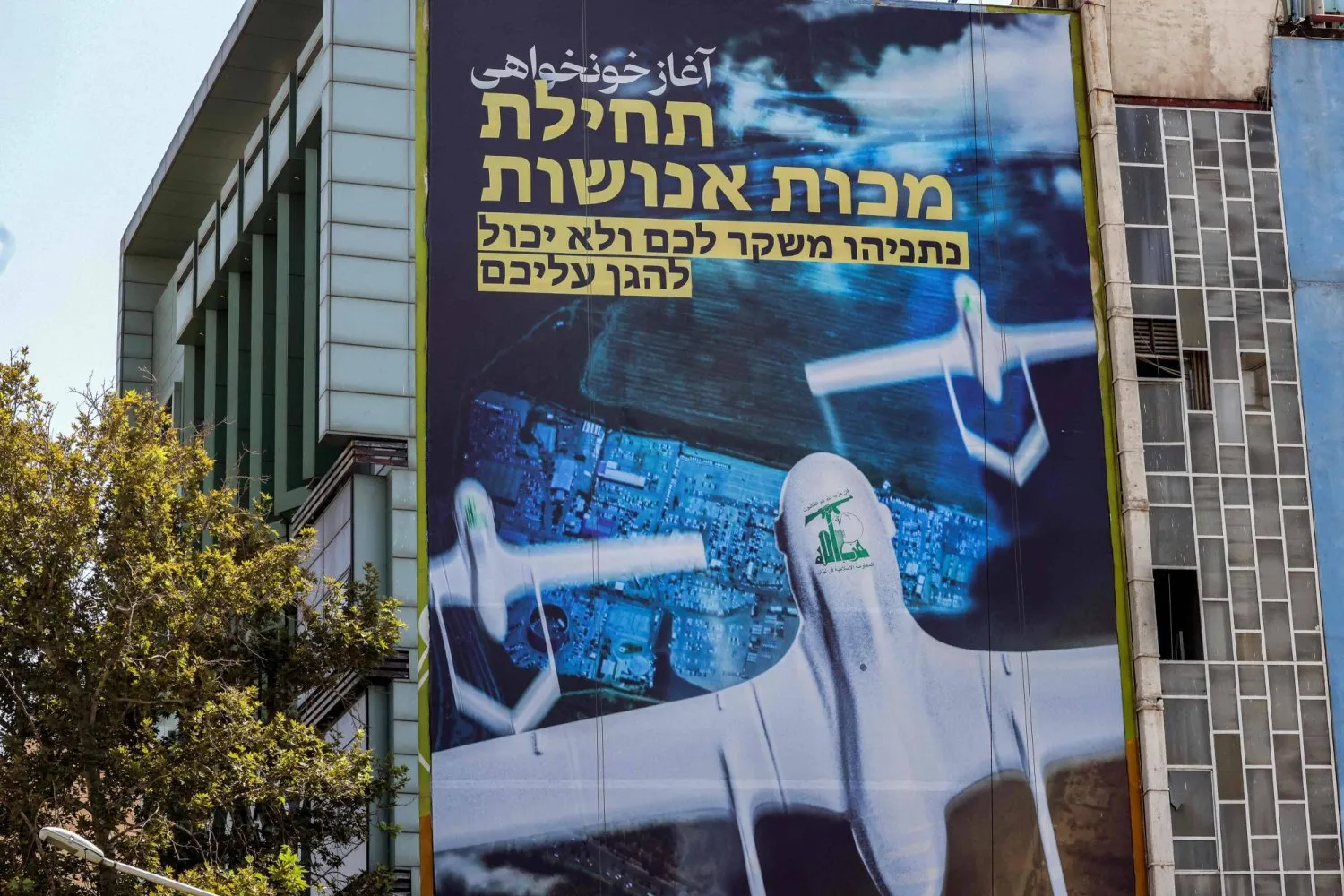 Tahran’ın Filistin Meydanı'ndaki bir duvarda Hizbullah logolu İHA’ları gösteren bir duvar resmi (AFP)