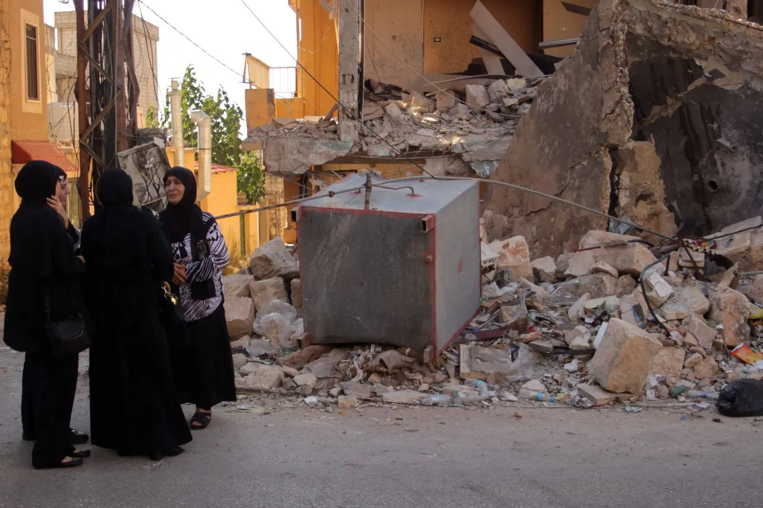 سيدات يقفن إلى جانب أحد المنازل المدمرة في بلدة الخيام (أ.ف.ب)