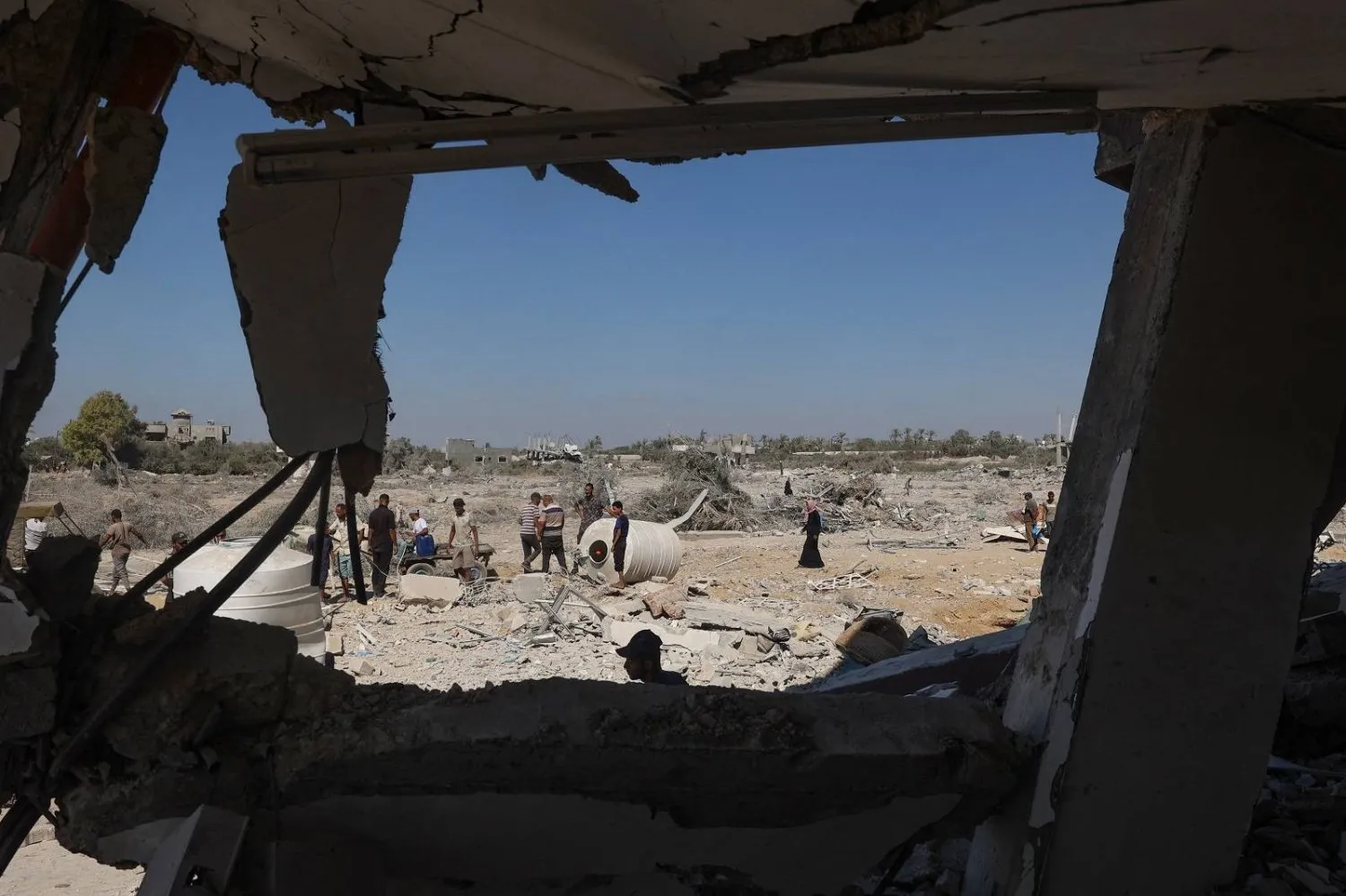 Filistinliler Gazze Şeridi'nin orta kesimindeki Deyr el-Balah'ın doğusundaki evlerinde enkazdan çıkarılabilecek eşya olup olmadığını kontrol ediyor. (AFP)